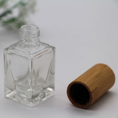 正方形のマニキュアのびんのタケ帽子は化粧品のガラス ビンに空のびんを構成する